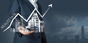 person holding a building with an arrow pointing up showing real estate trends rising