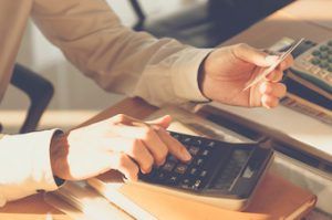 person sitting in front of desk on calculator looking for ways to improve credit to buy a home