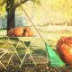 small patio table with pumpkins, leaves and a rake