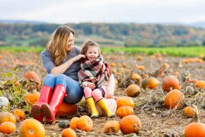 mom and daughter sitting in field of pumpkins