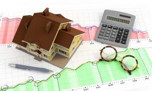 small toy home and calculator on a graph 