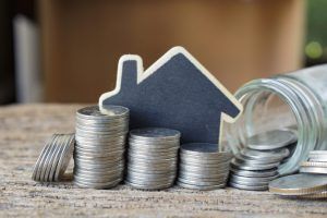 coins in a jar in front of a toy sized home