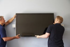 two men mounting a tv to the wall