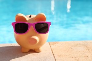 piggy bank sitting beside a luxury real estate pool 
