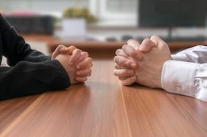 man and women sitting across from the table negotiating home sale