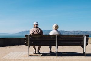 older couple sitting in bench by water